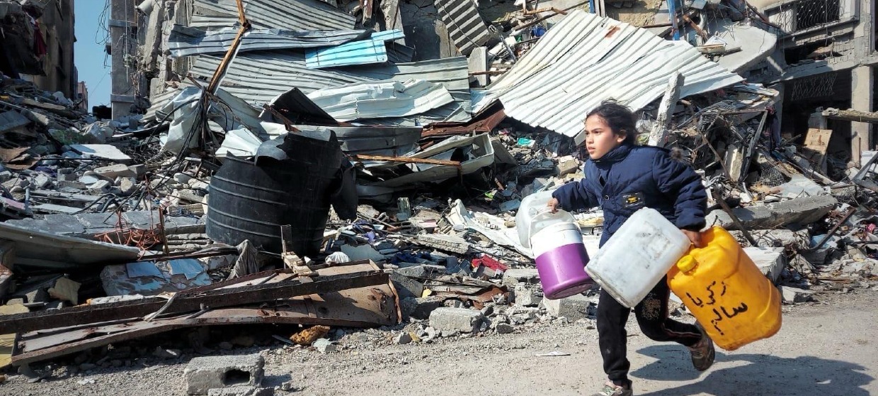 A little girl runs looking for drinking water amid the rubble of Beit Lahia (Credit: Saïd Ahmad Kilani)